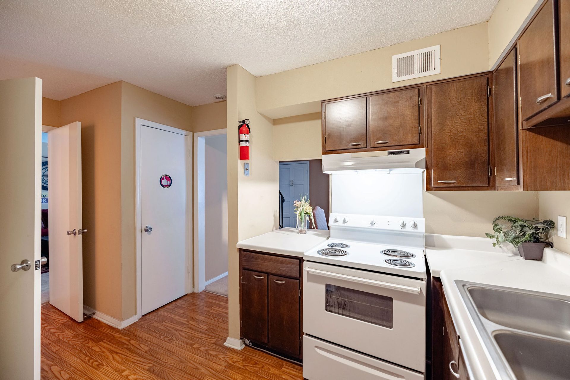 A kitchen with a stove and a sink and a fire extinguisher on the wall