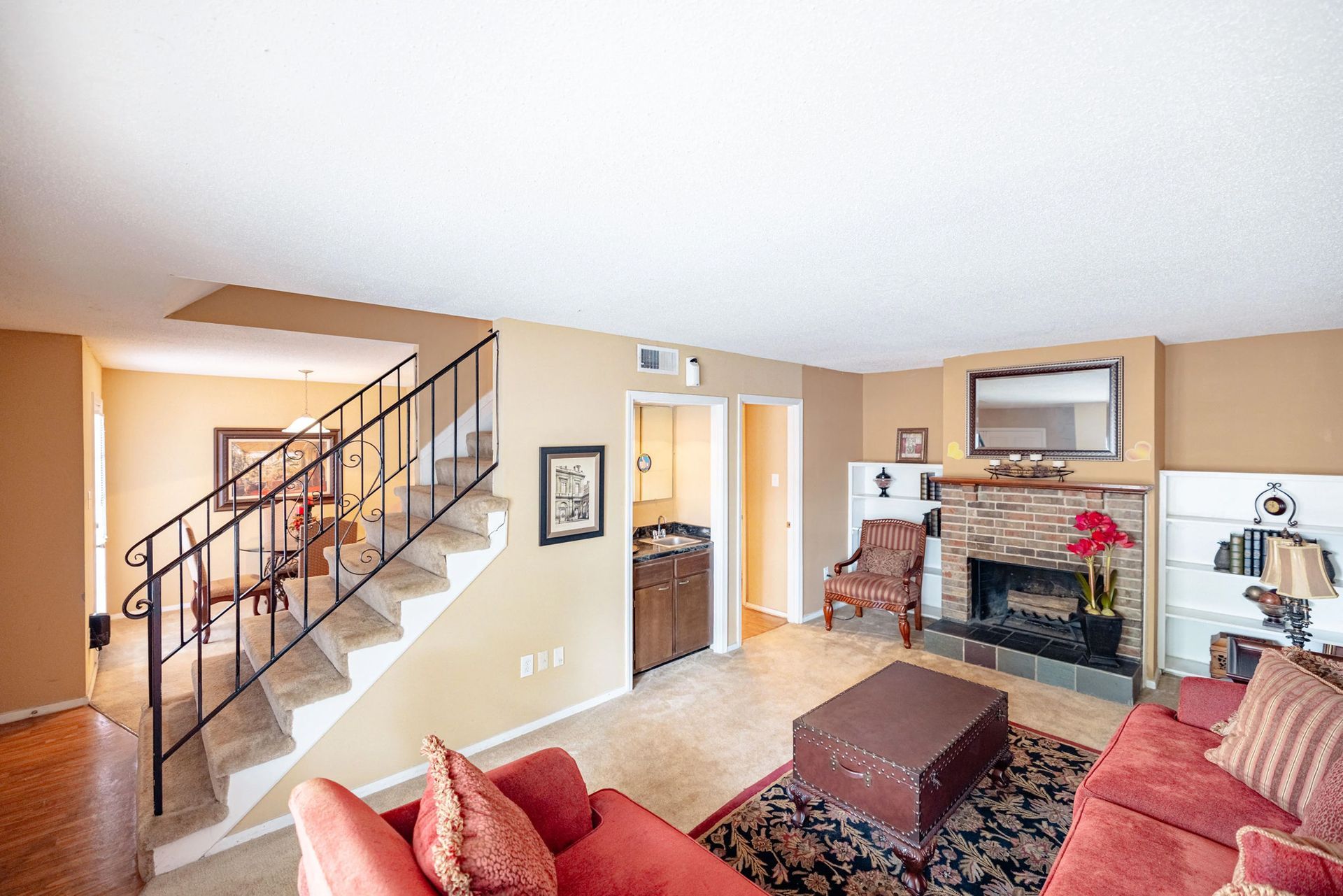 A living room with a red couch , fireplace and stairs.