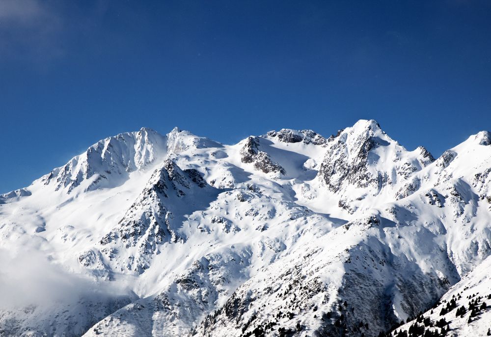 Eine schneebedeckte Bergkette mit einem blauen Himmel im Hintergrund