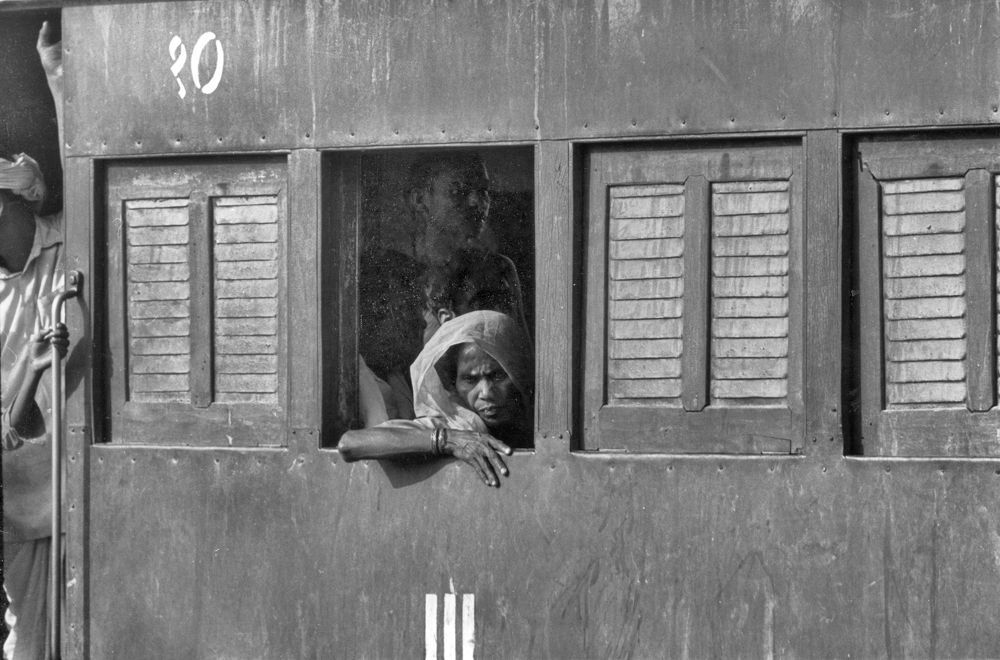 Ein Schwarzweissfoto von Menschen, die aus einem Zugfenster schauen
