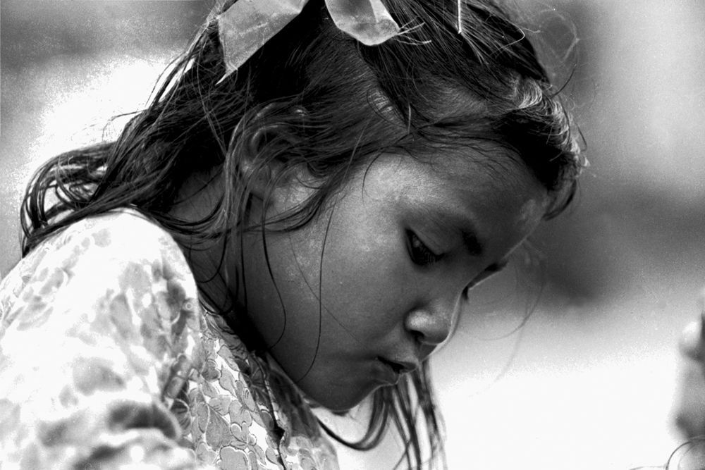 Ein Schwarzweissfoto eines jungen Mädchens mit einer Blume im Haar.