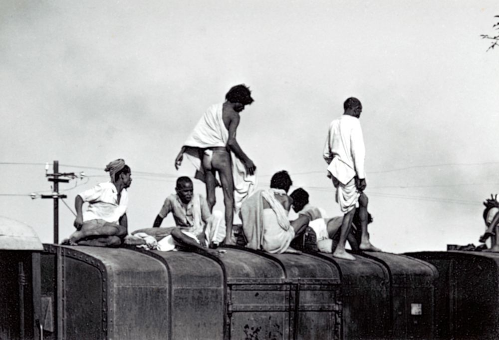 Eine Gruppe von Menschen sitzt auf dem Dach eines Zugwaggons.