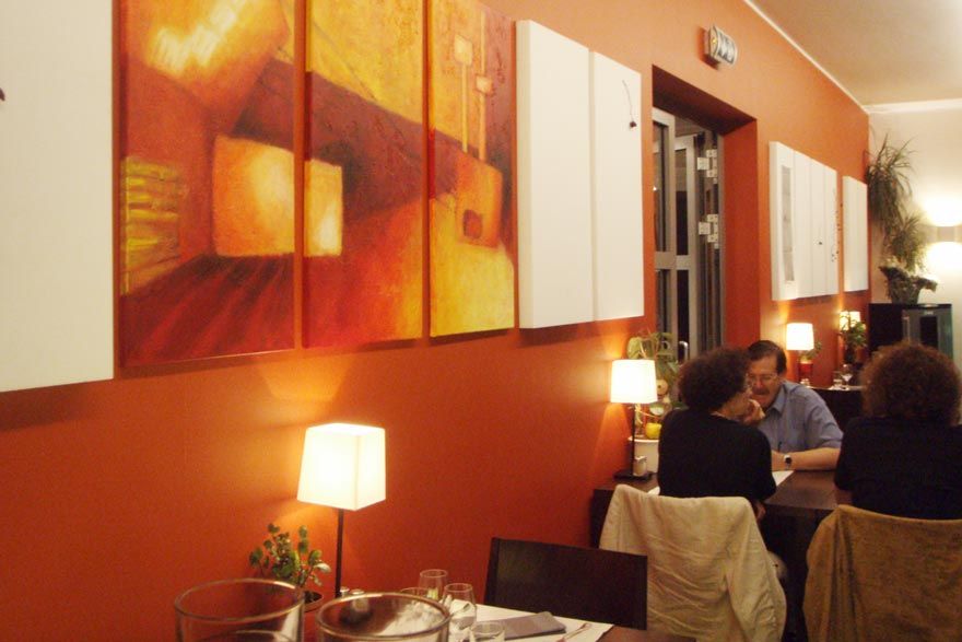 Menschen sitzen an Tischen in einem Restaurant mit Gemälden an der Wand