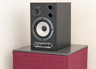 Ein schwarzer Lautsprecher sitzt auf einer roten Box.