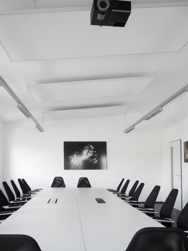 Ein Konferenzraum mit einem langen weissen Tisch und schwarzen Stühlen