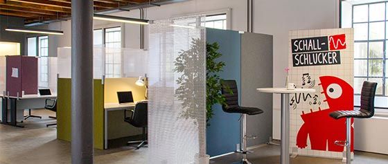 Ein Raum mit einem Tisch und Stühlen darin und einem roten Monster an der Wand.