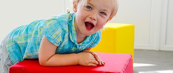 Ein kleines Mädchen liegt auf einem roten Block.