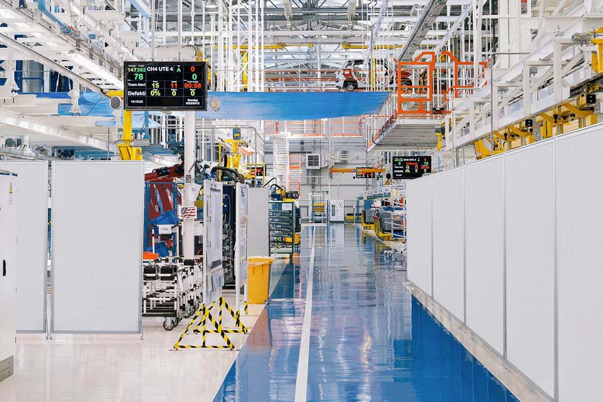 Eine grosse leere Fabrik mit blauem Boden und weissen Wänden.