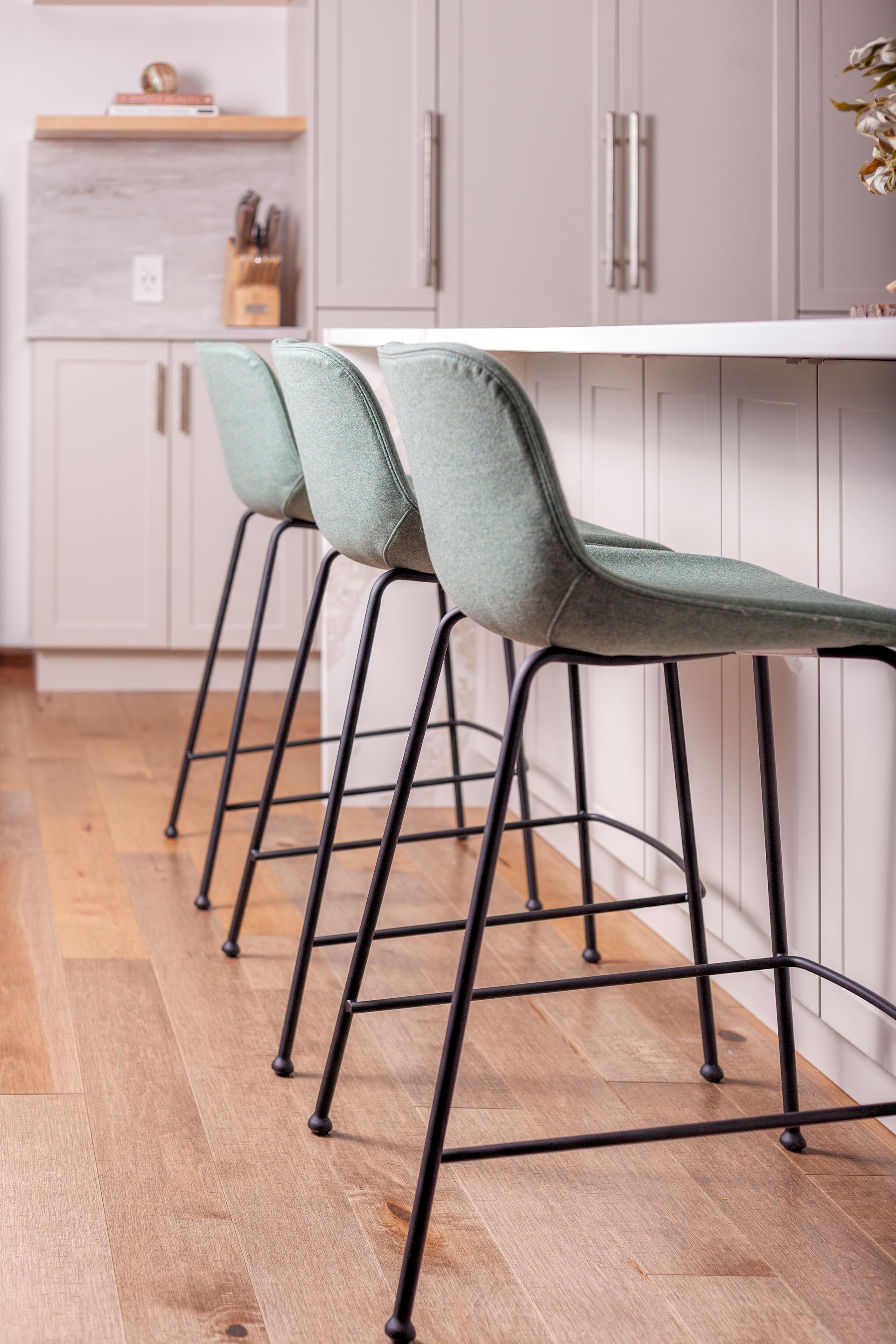 three green bar stools are lined up next to each other in a kitchen .