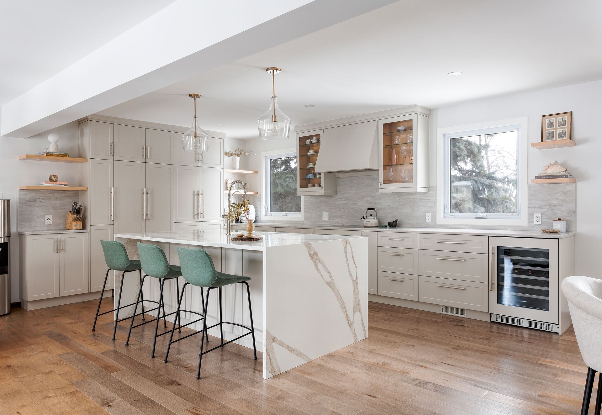 a kitchen with white cabinets , marble counter tops , and wooden floors .
