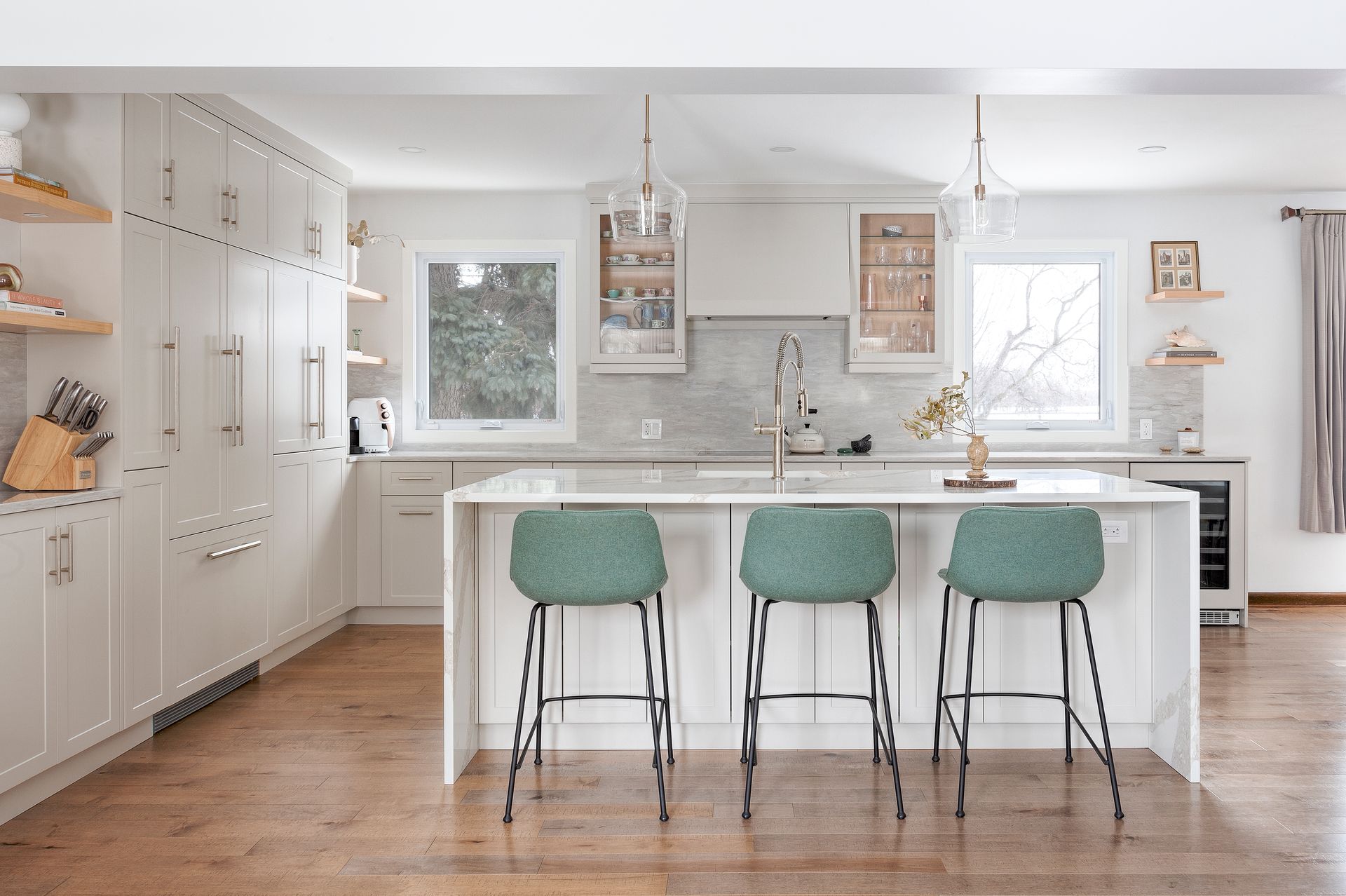 a kitchen with white cabinets , green stools and a large island .