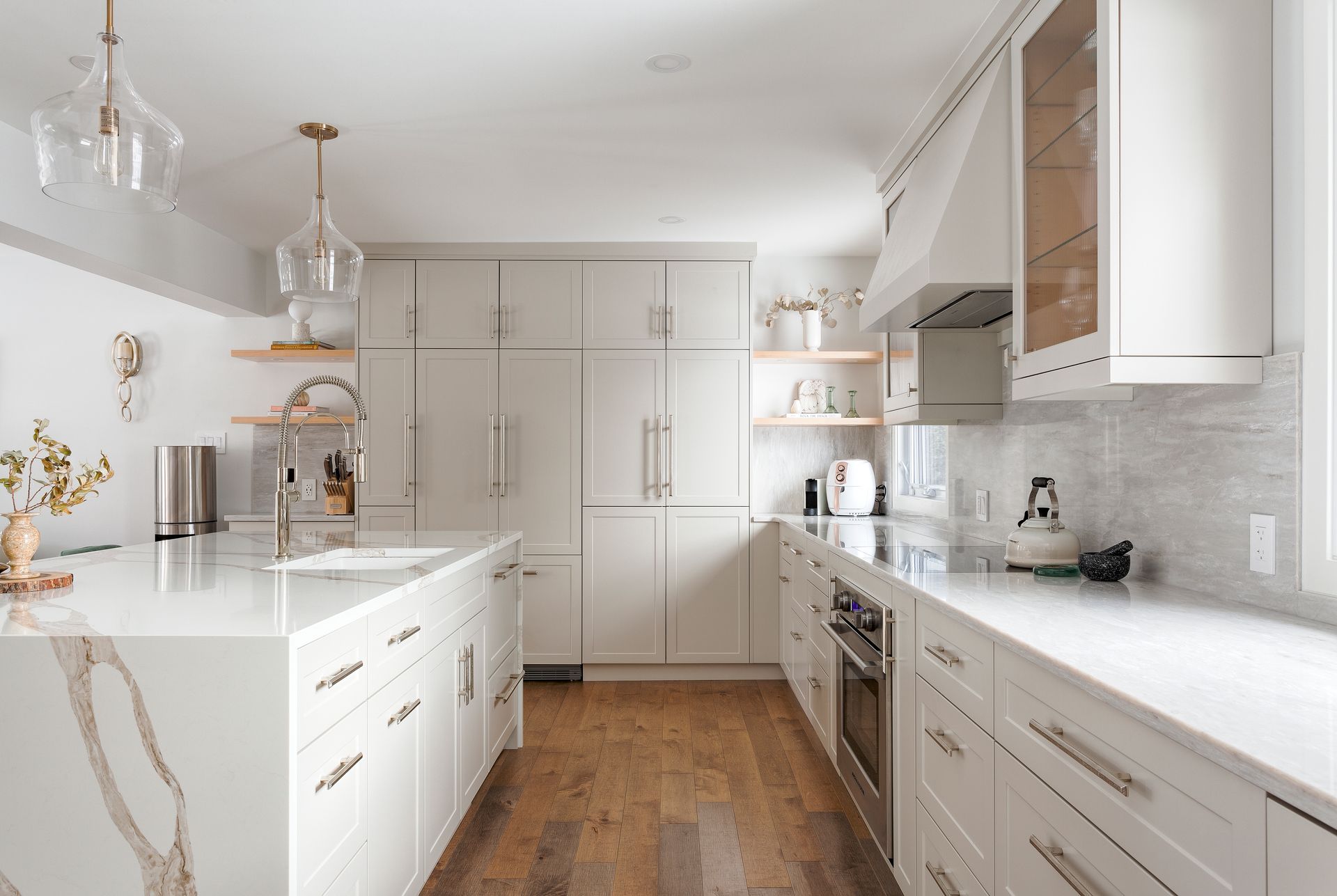 a kitchen with white cabinets , white counter tops , stainless steel appliances , and hardwood floors .