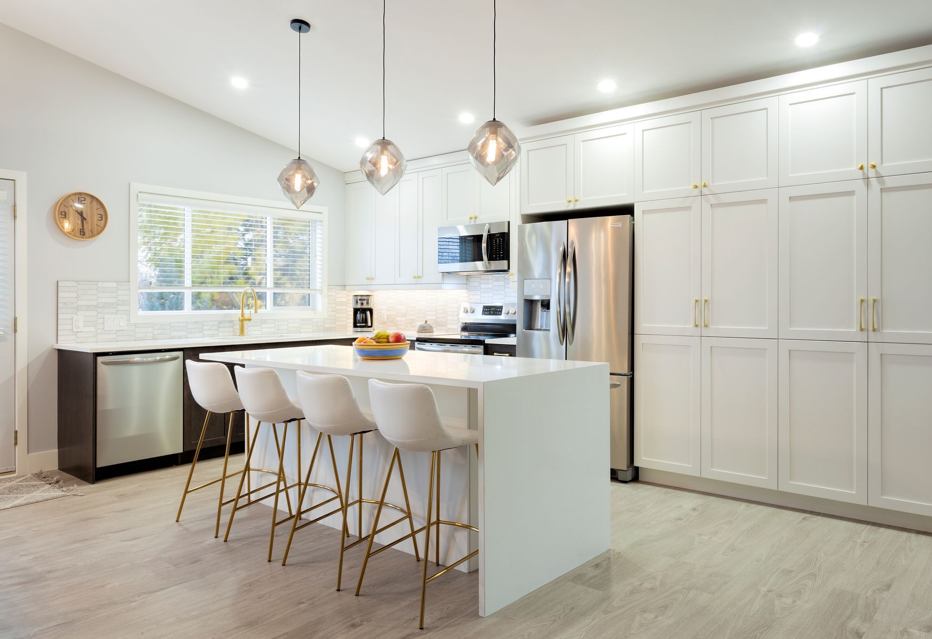 A kitchen with white cabinets, stainless steel appliances, and a large island.