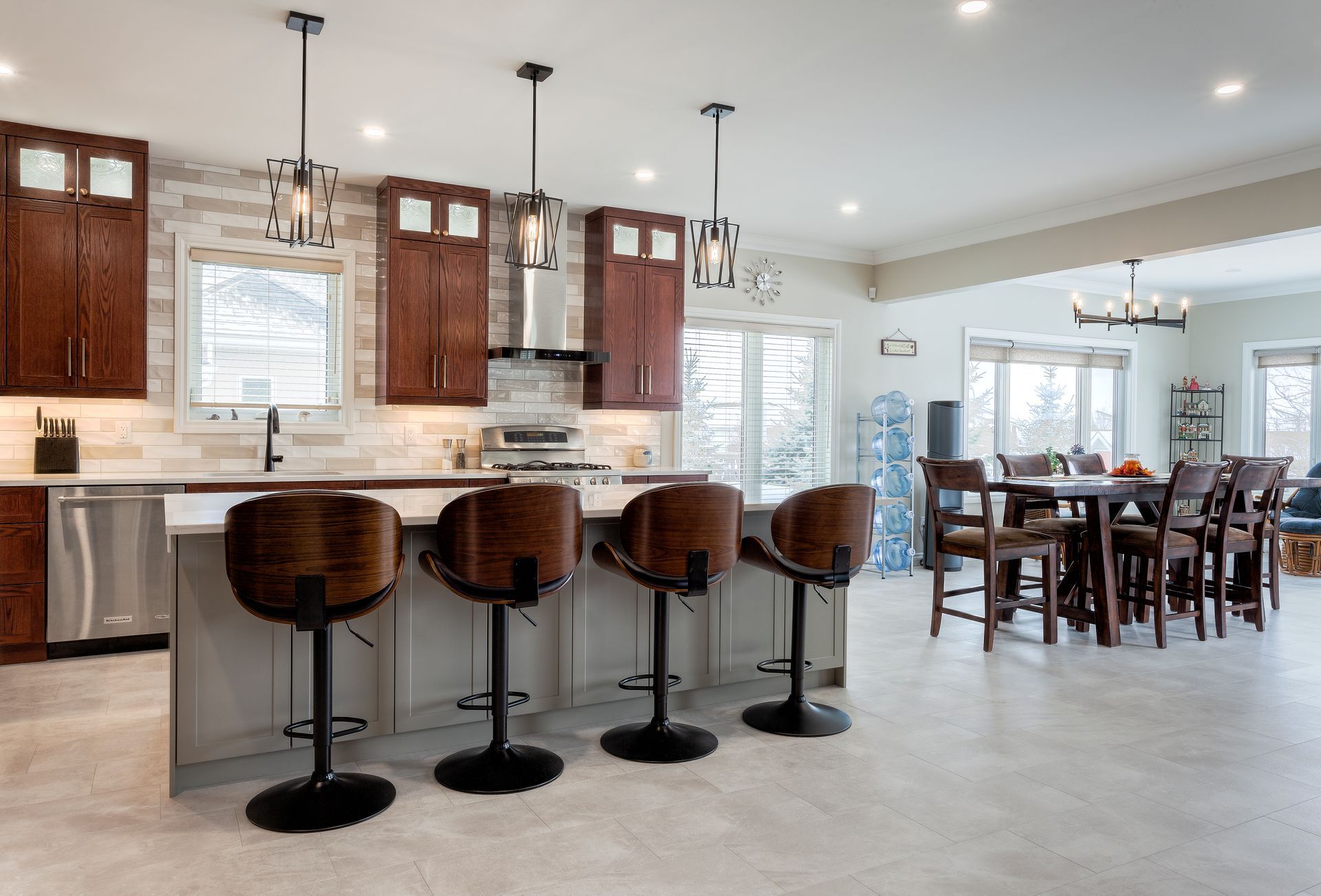 A kitchen with a large island, stools, a table and chairs.