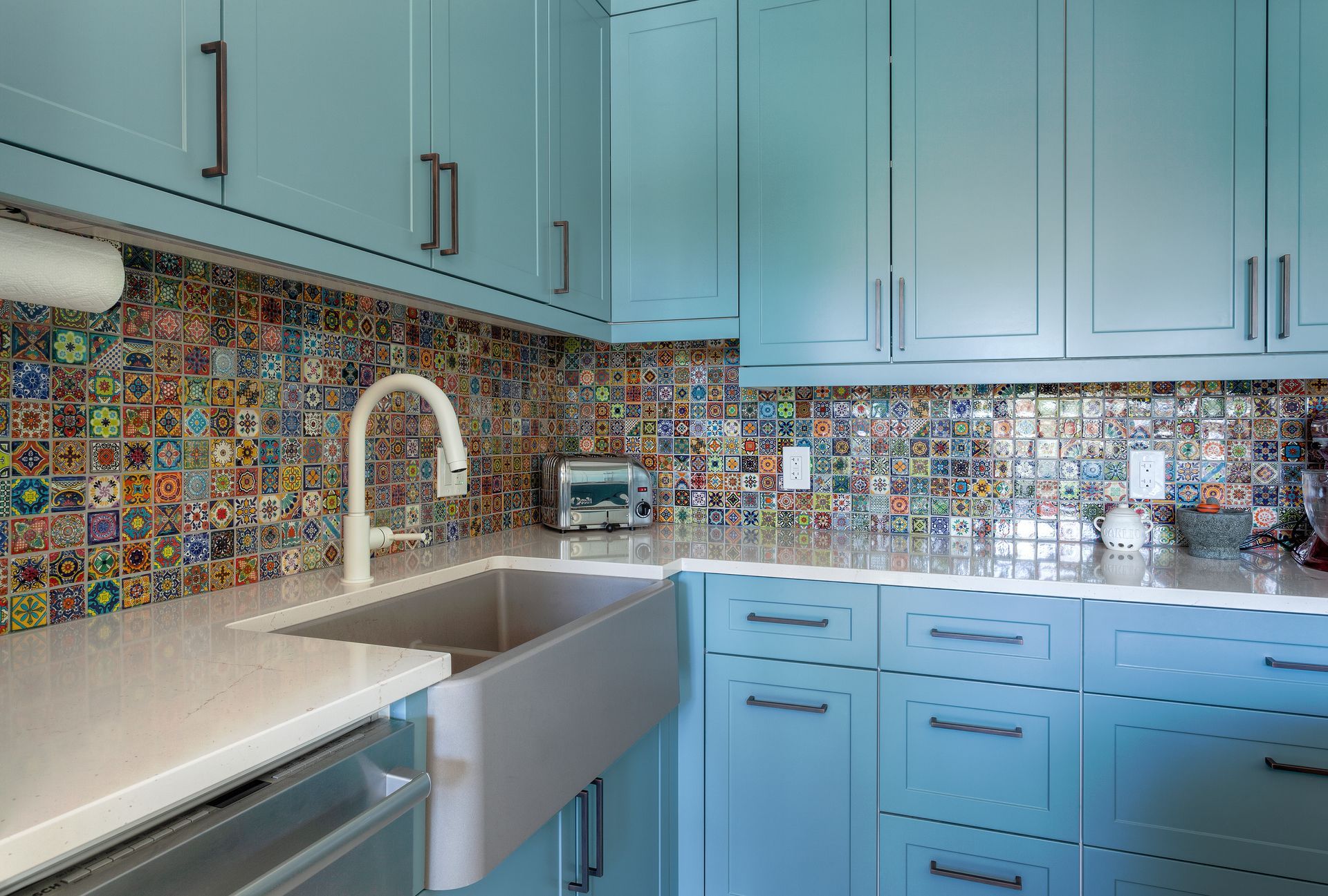 A kitchen with blue cabinets , a sink , and a toaster oven.