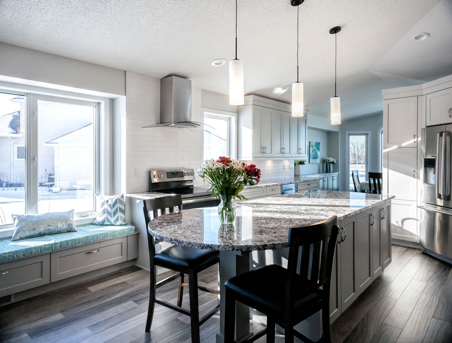 A kitchen with a table and chairs and a vase of flowers on the counter.