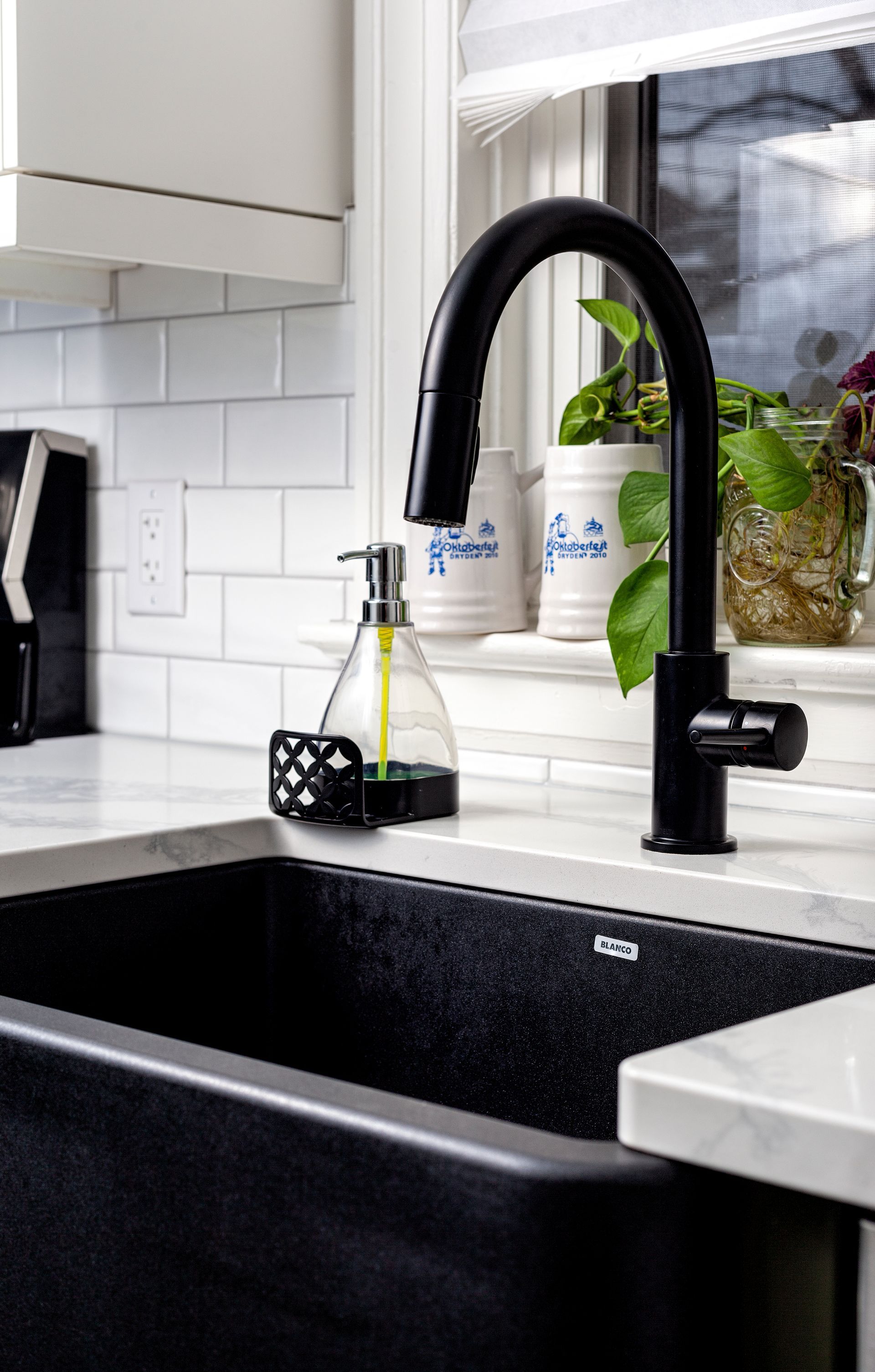 A kitchen sink with a black faucet and a soap dispenser on the counter.