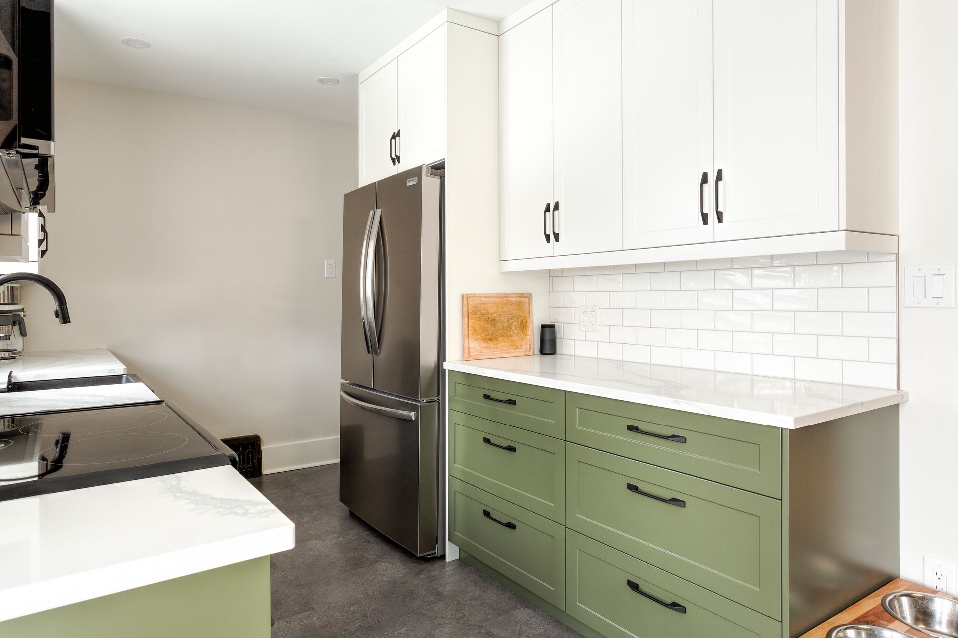 A kitchen with green cabinets and a stainless steel refrigerator.