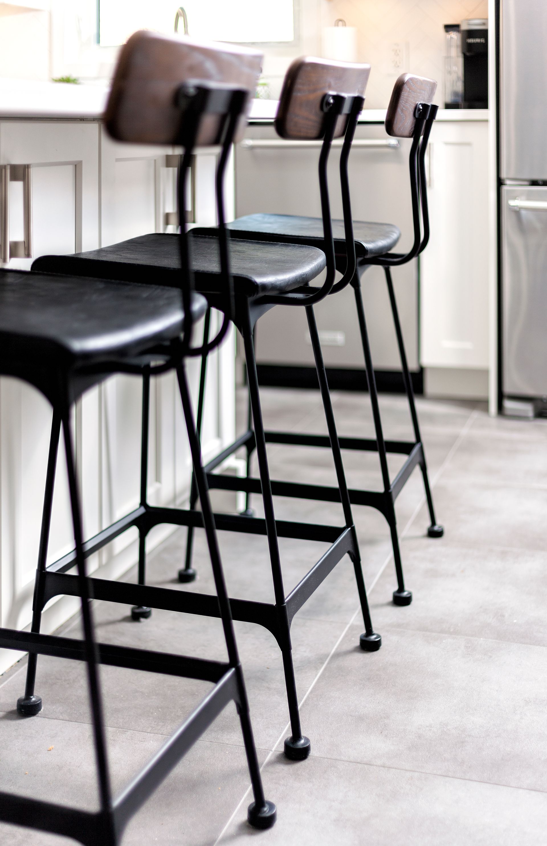 three black bar stools are lined up in a kitchen .