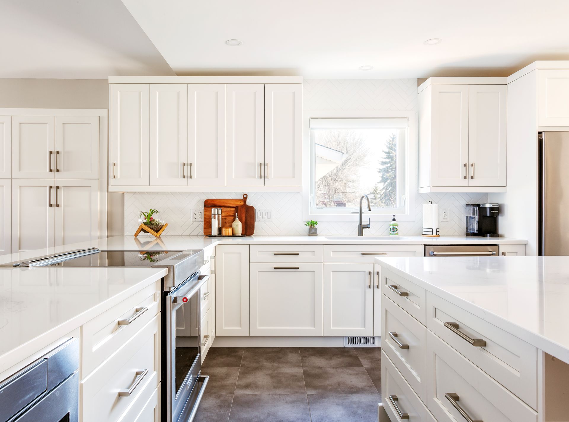 a kitchen with white cabinets , stainless steel appliances , and a large island .