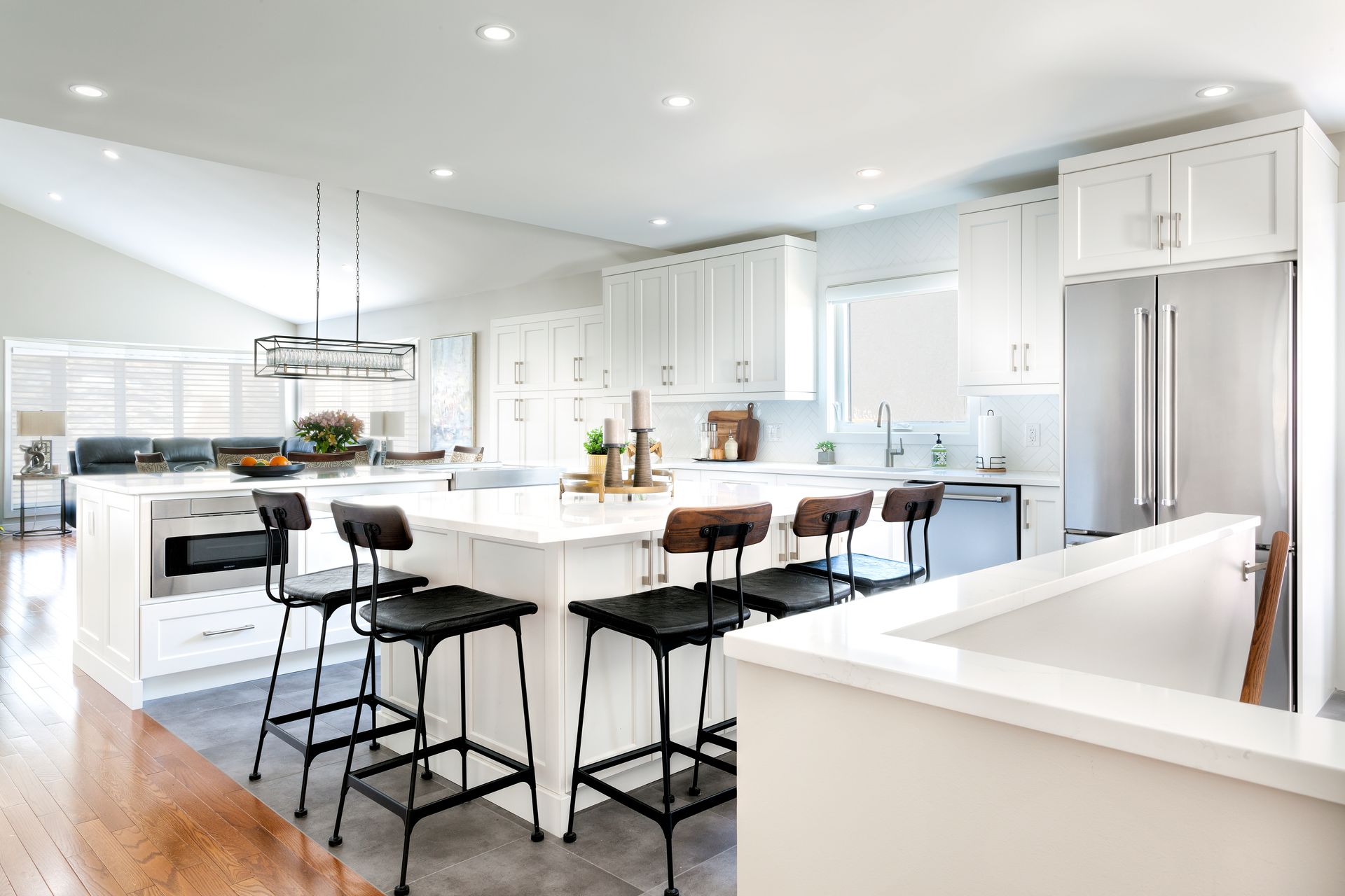 a kitchen with white cabinets and black stools and a large island .