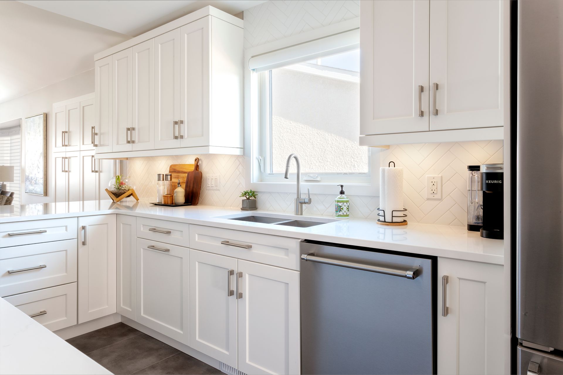 a kitchen with white cabinets , stainless steel appliances , a sink , and a window .