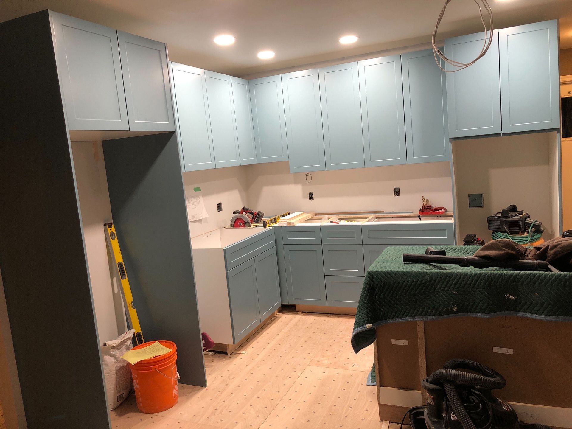 A kitchen with blue cabinets and wooden floors is being remodeled.