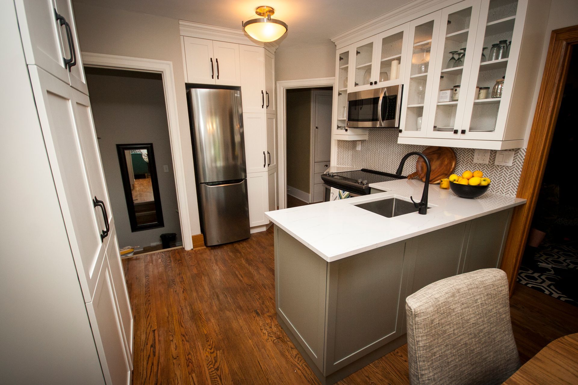 A kitchen with white cabinets , stainless steel appliances , a sink and a refrigerator.