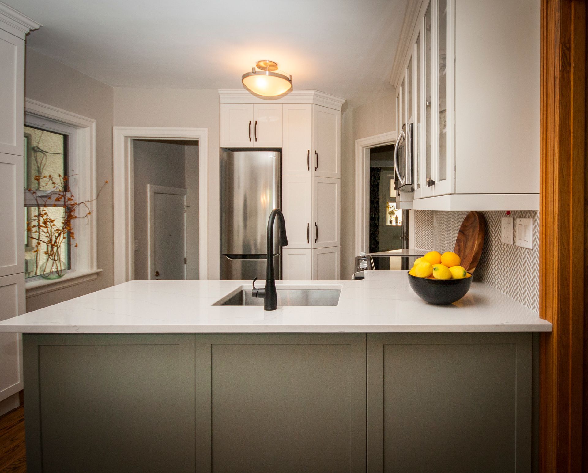 A kitchen with a sink and a bowl of lemons on the counter.