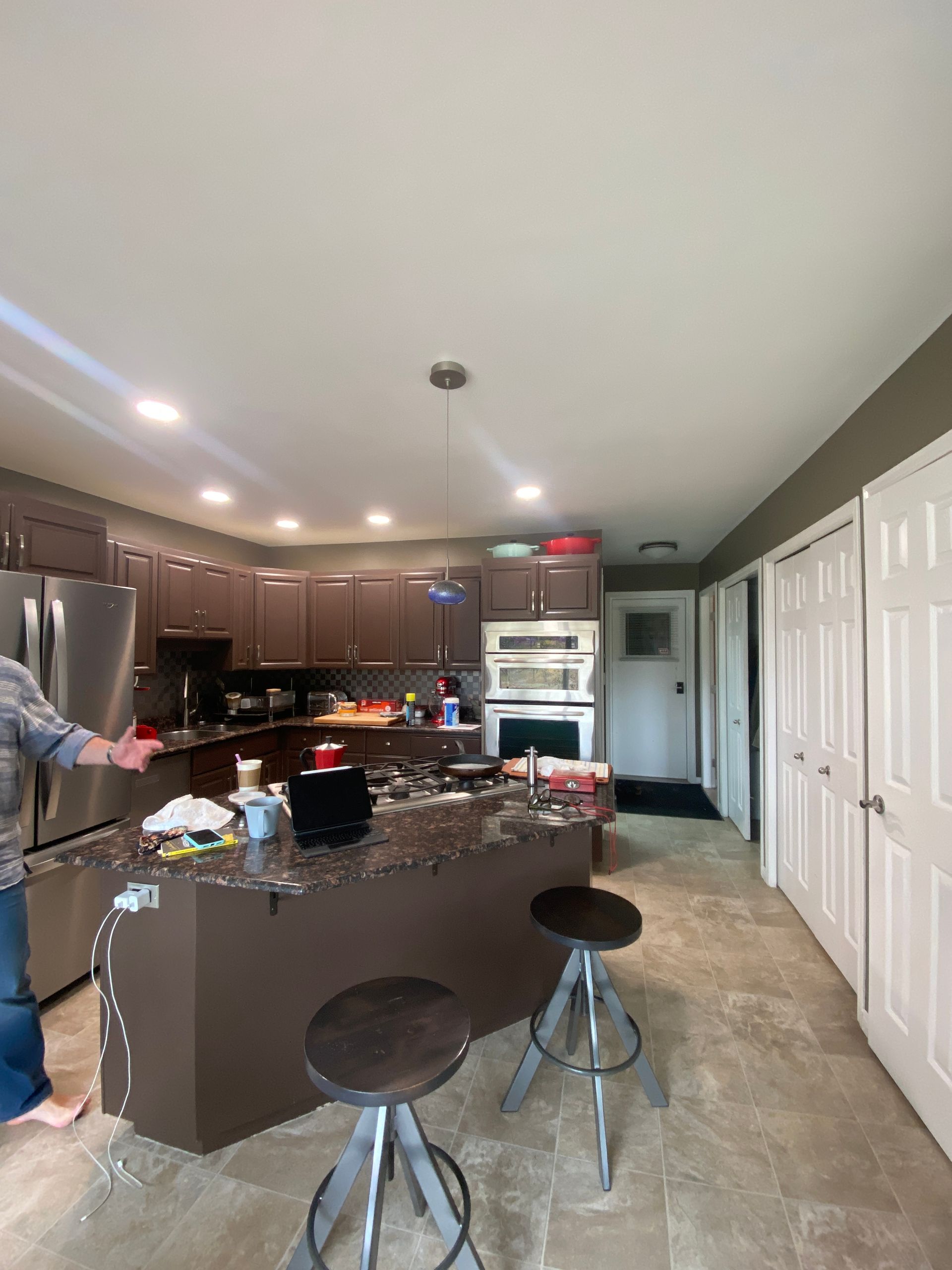 A man is standing in a kitchen with a large island and stools.