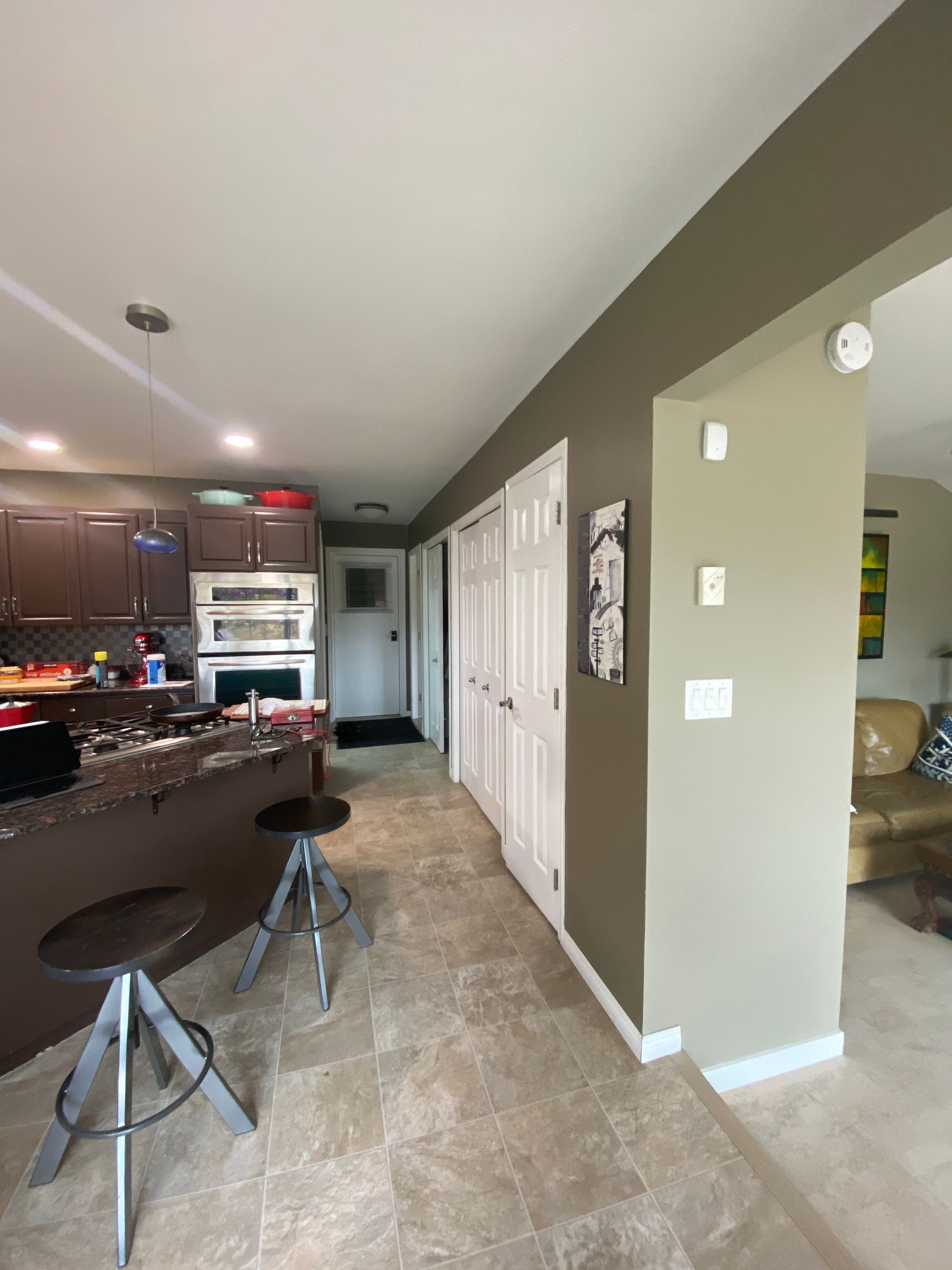 A kitchen with a stove , microwave , refrigerator and stools.