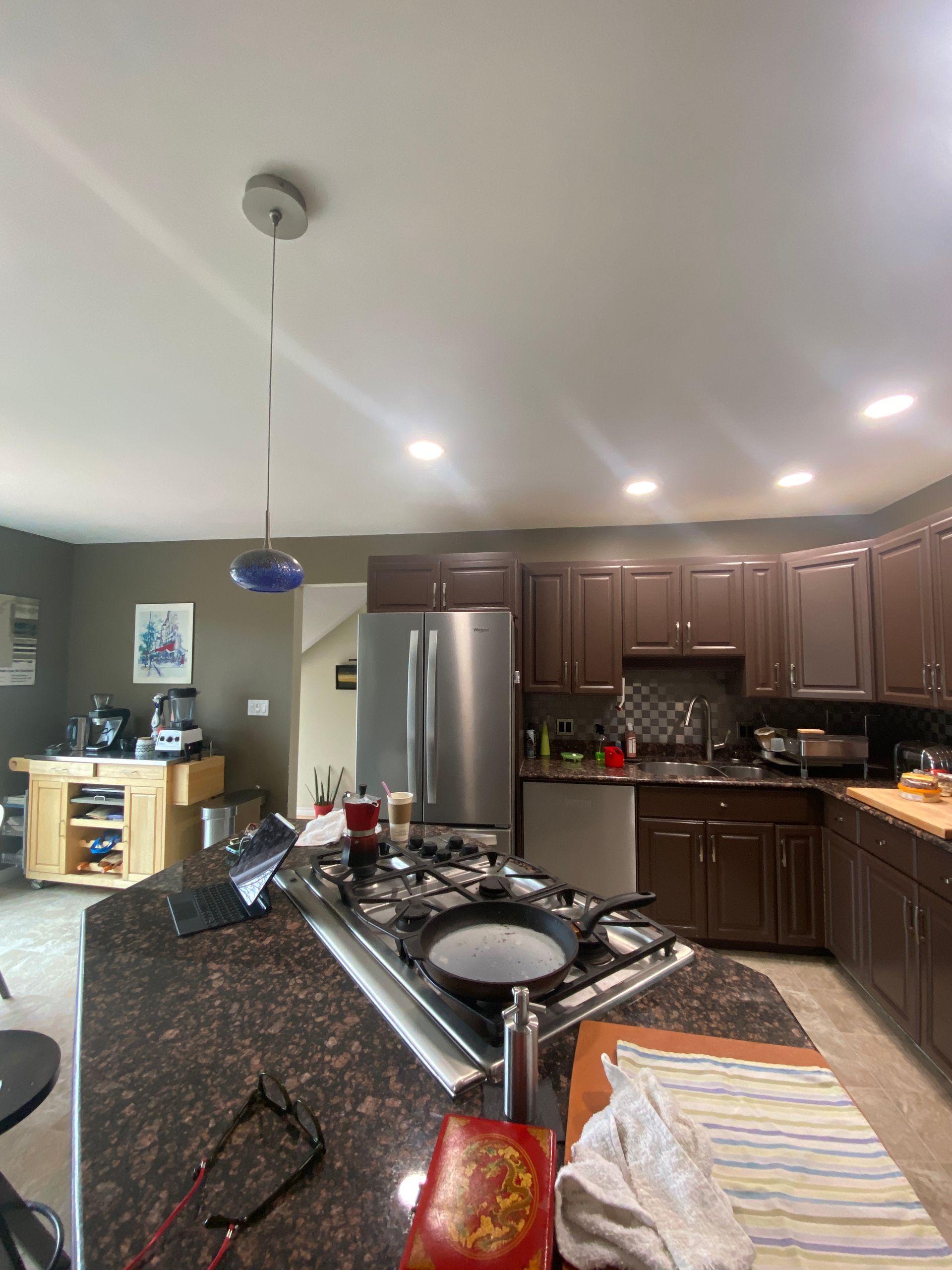 A kitchen with brown cabinets and a stainless steel refrigerator