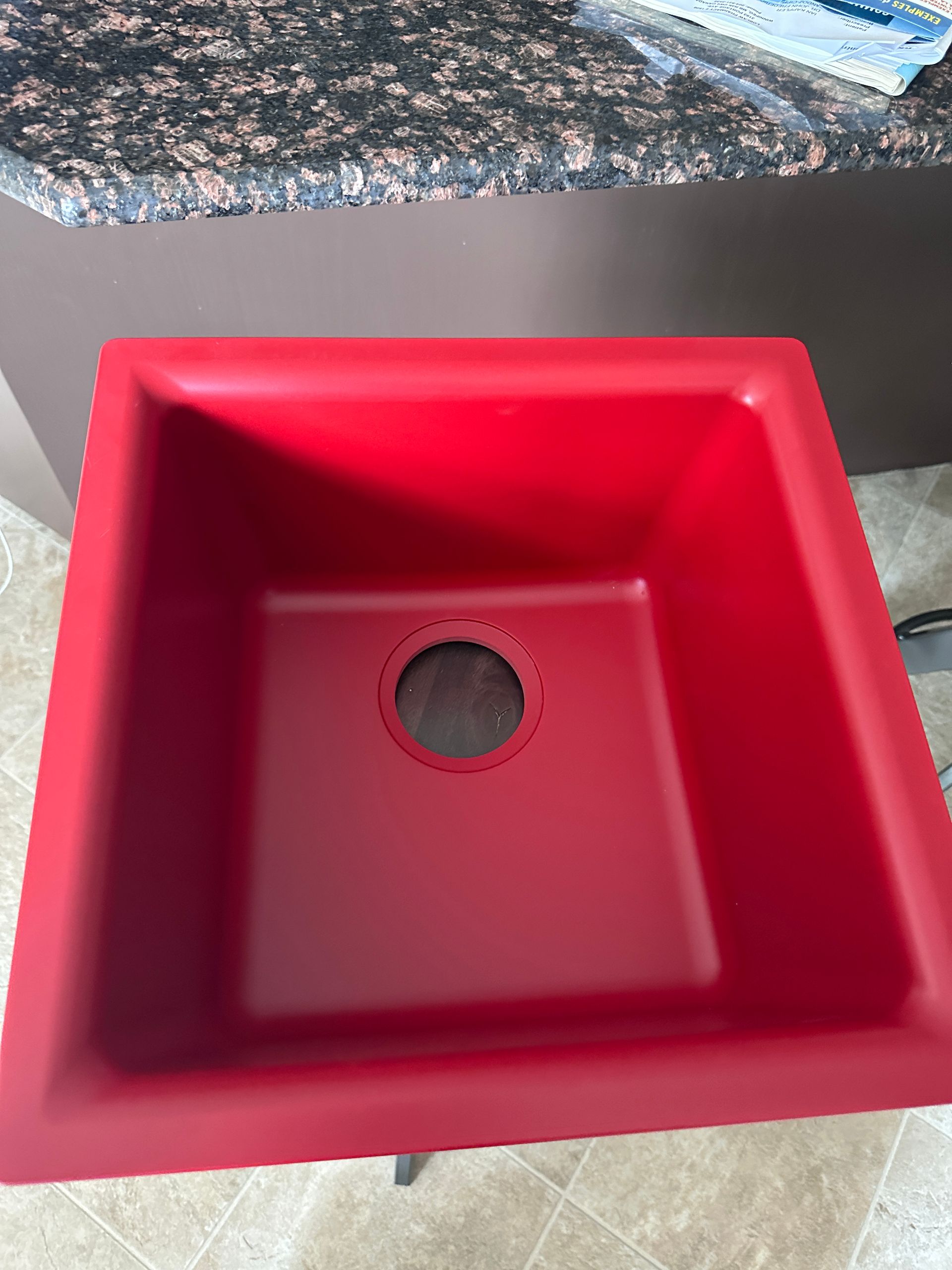 A red sink is sitting on top of a counter.