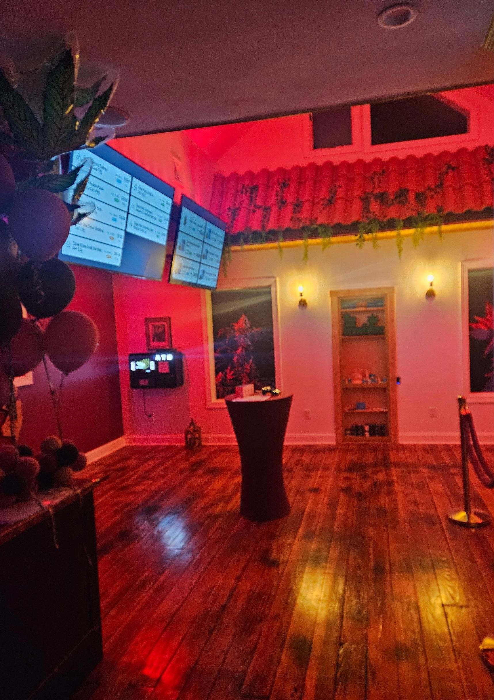 A room with a wooden floor, TV's with Menus, and a red light on the ceiling.