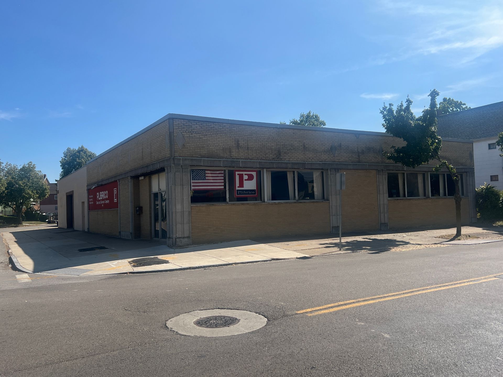 A small, weathered building with an American flag in the window, located on a street.