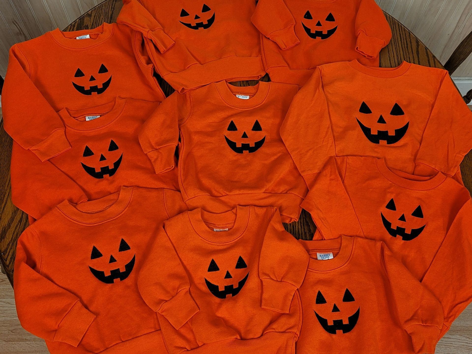 A bunch of orange sweaters with black pumpkins on them
