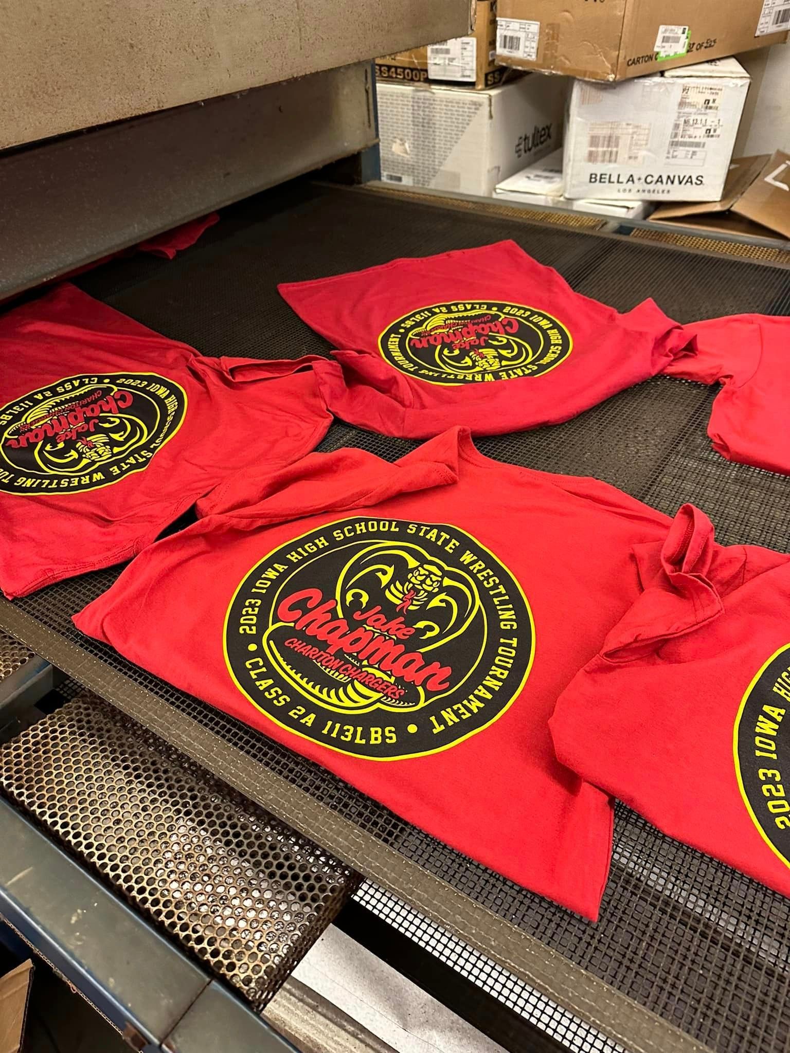A bunch of red shirts are sitting on a conveyor belt