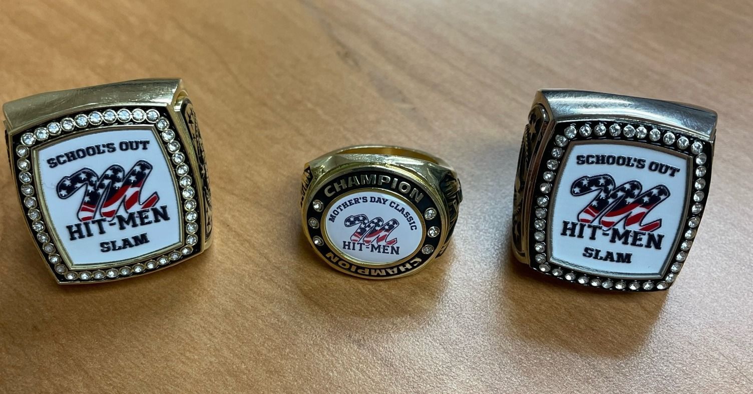 Three championship rings are sitting on a wooden table.
