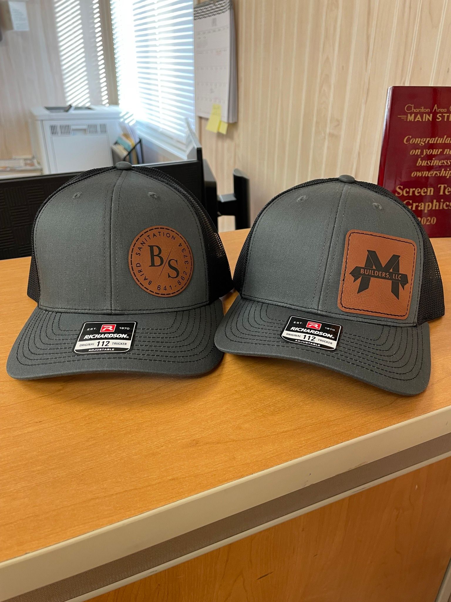 Two hats are sitting on a wooden table.