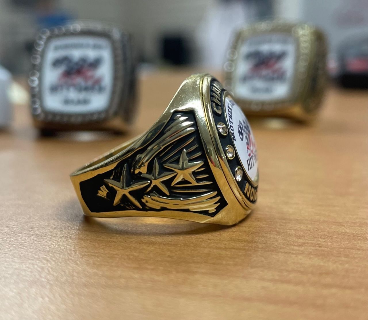 A gold ring with three stars on it sits on a wooden table