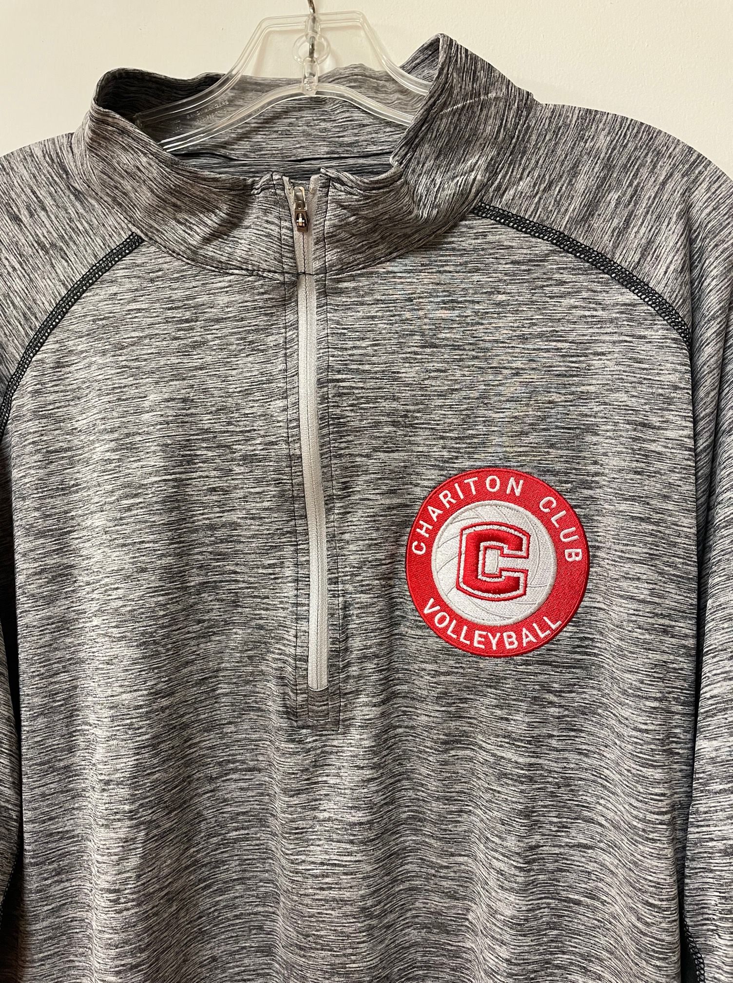 A gray sweatshirt with a red g on it is hanging on a hanger.