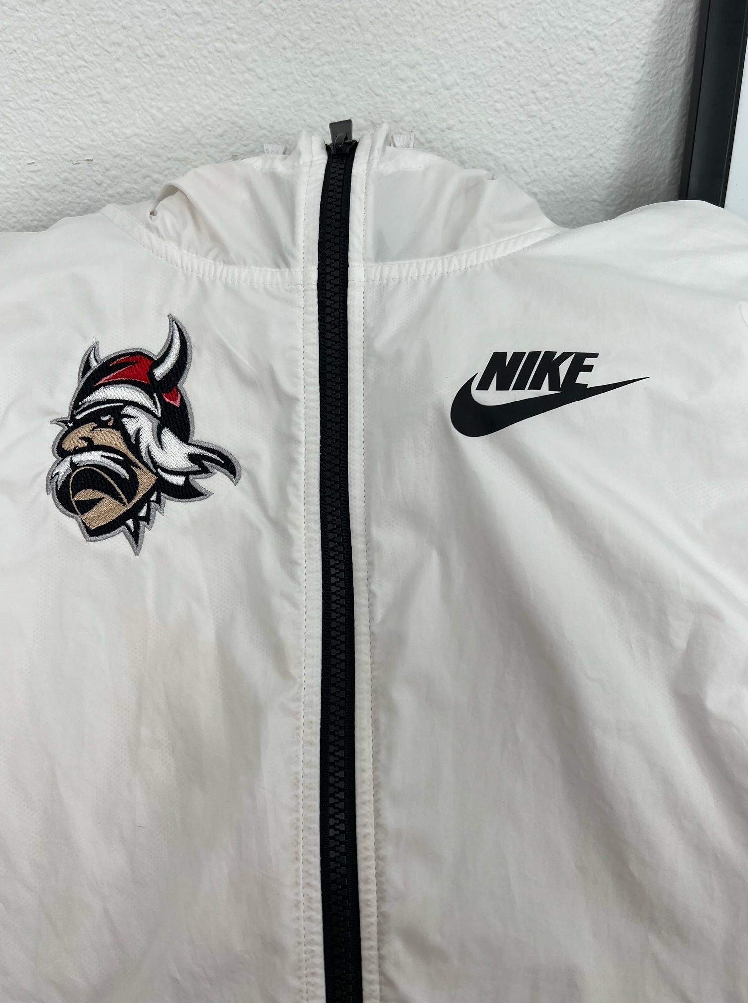A white nike jacket with a viking head on it