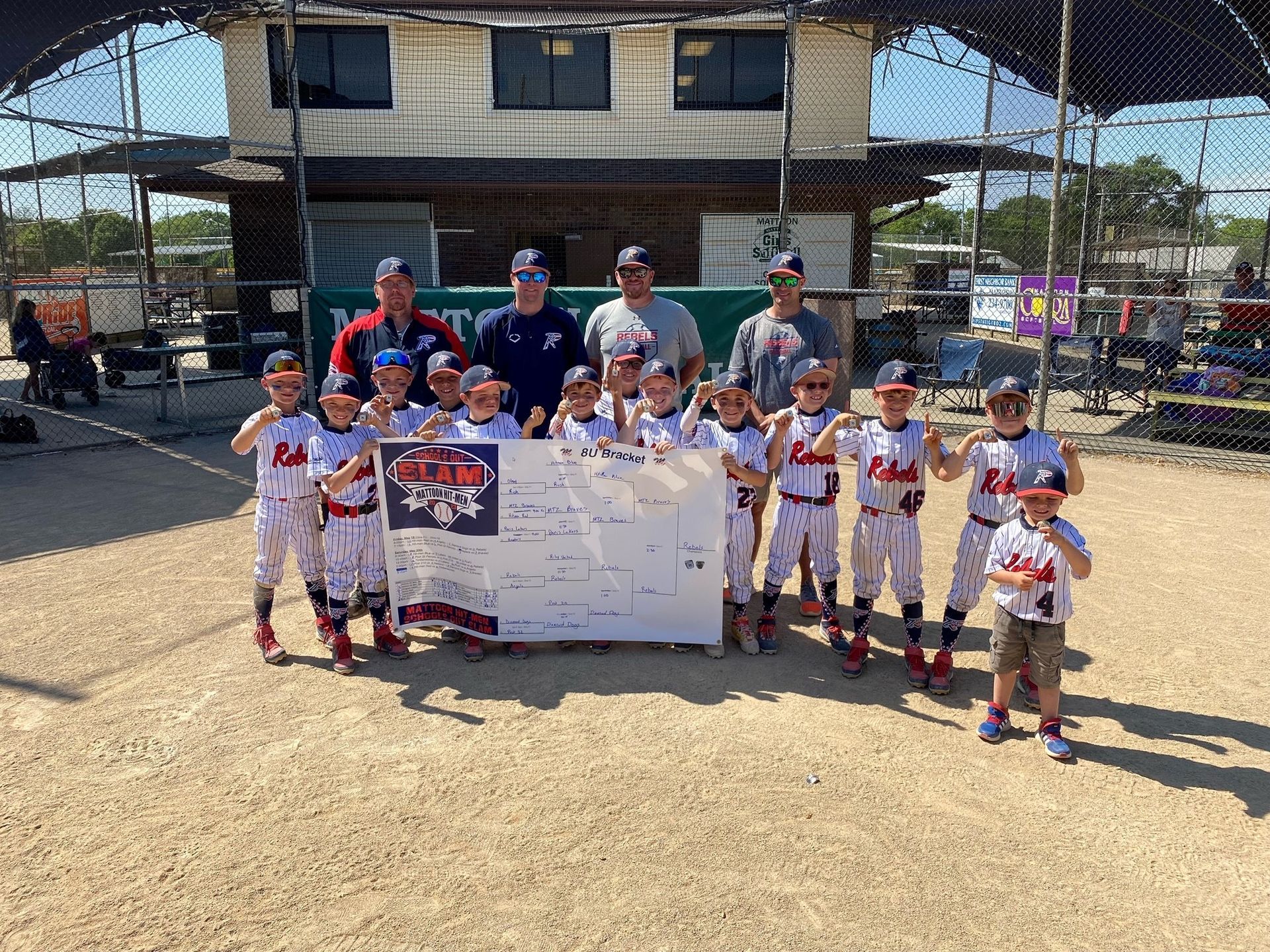 A group of young boys are posing for a picture on a baseball field.