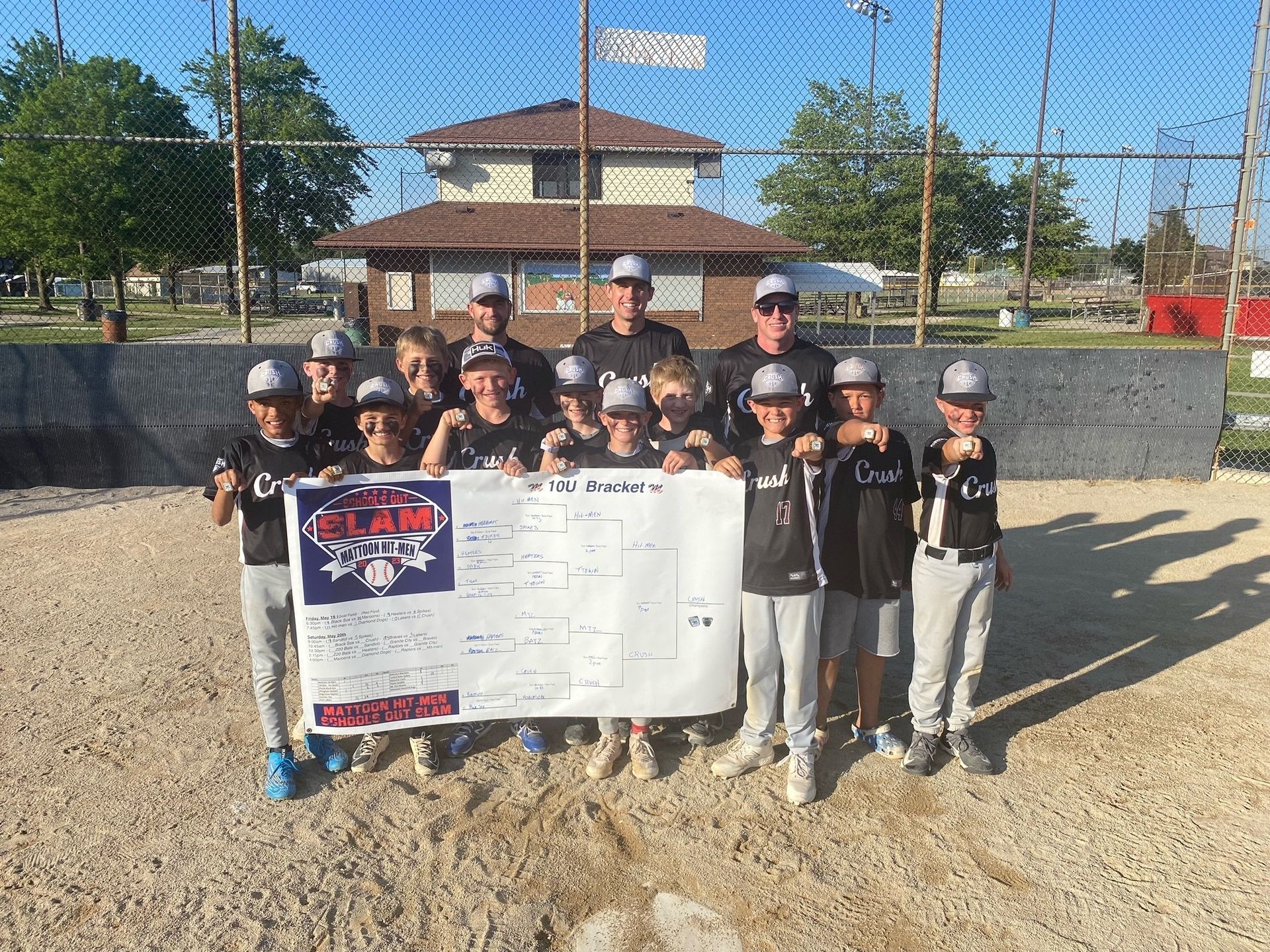 A group of young boys are posing for a picture on a baseball field.