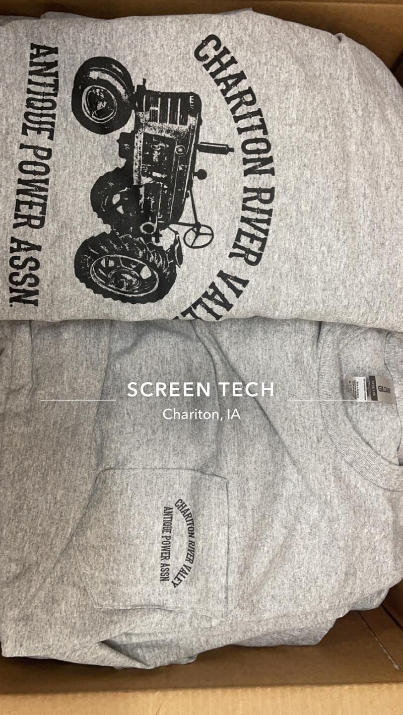 A gray shirt with a tractor on it is in a box.