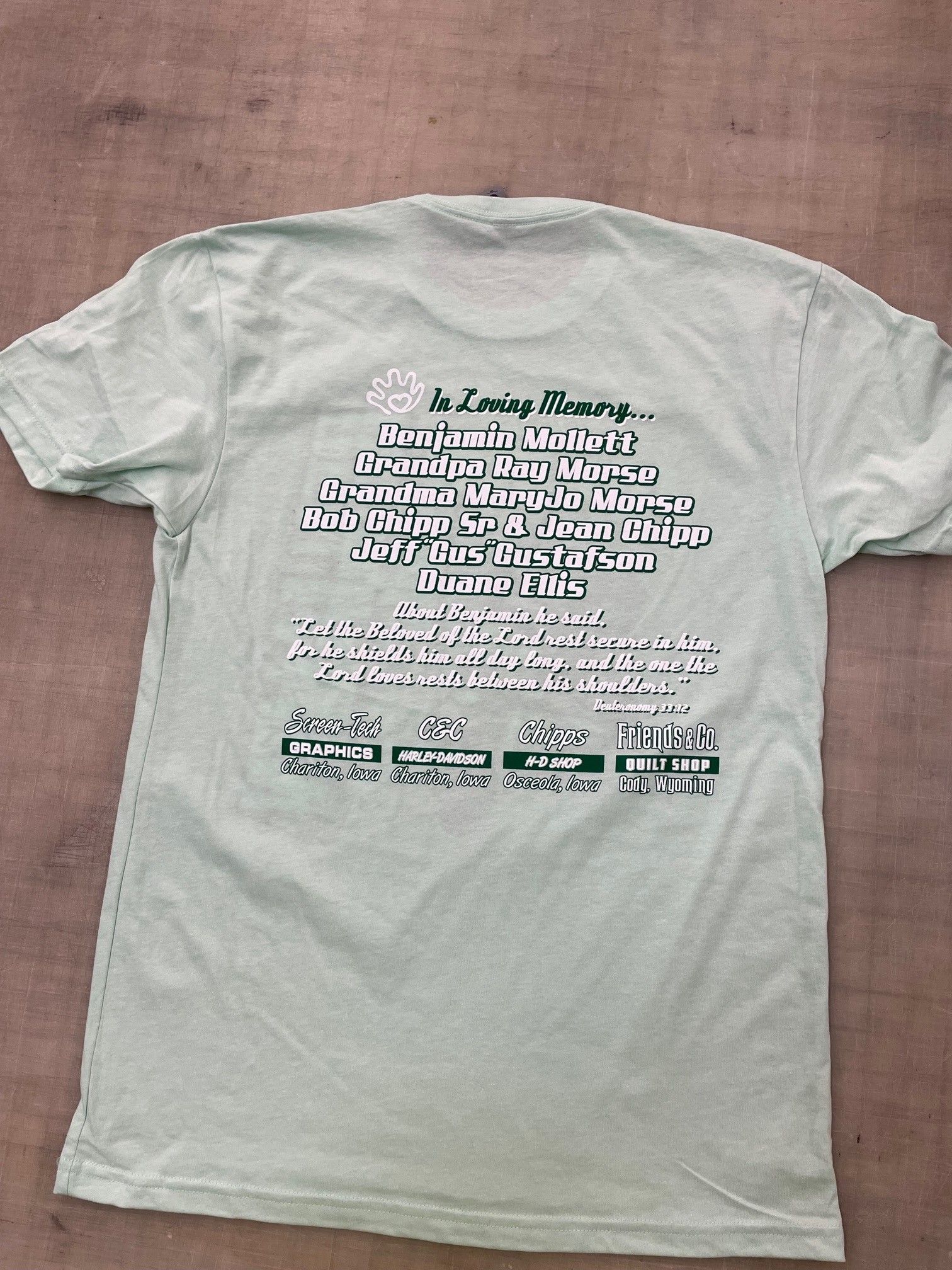 The back of a white t-shirt with green writing on it.