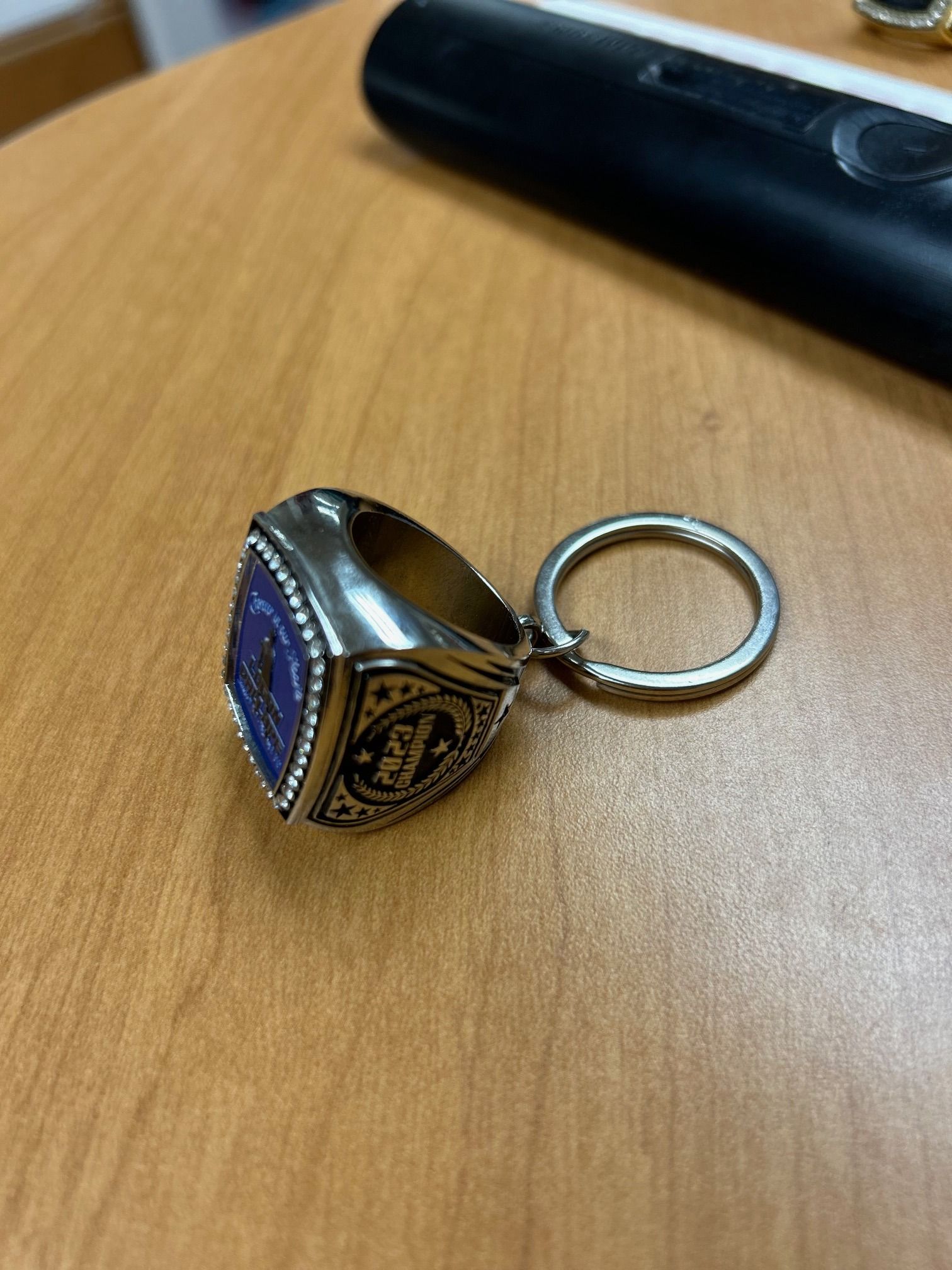 A ring with a keychain attached to it is on a wooden table.