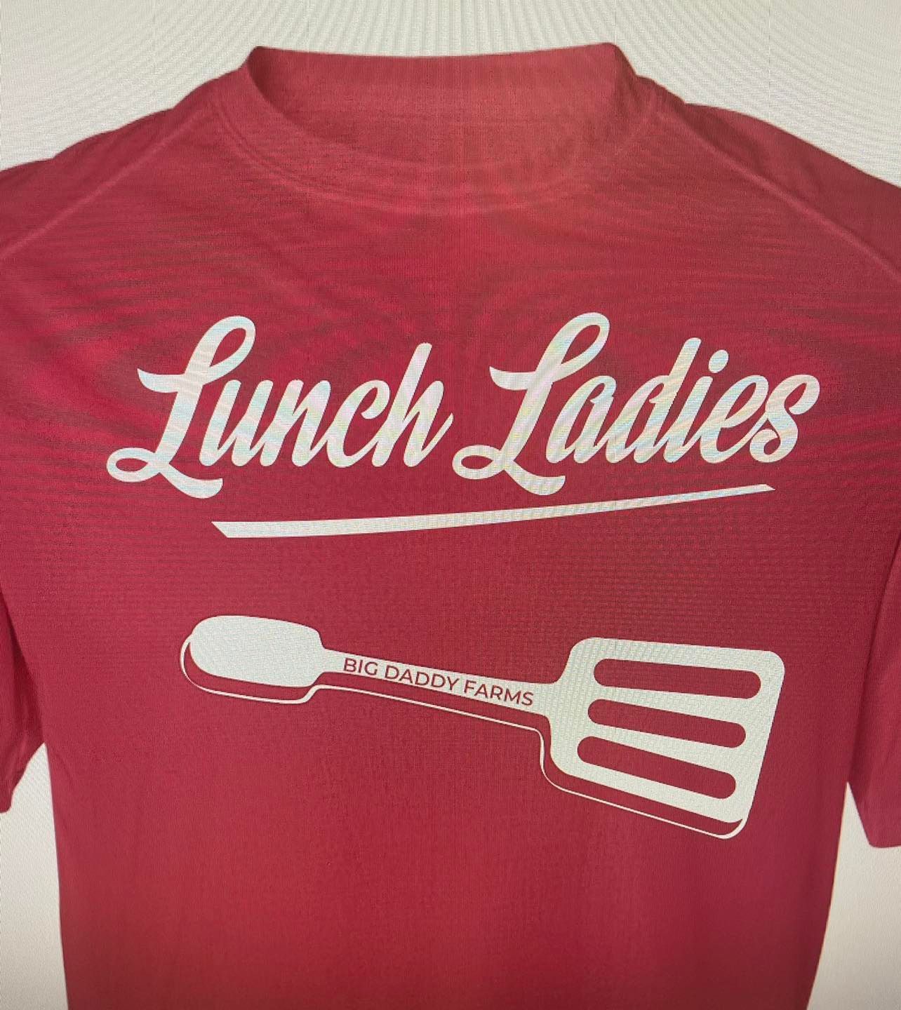 A red shirt that says lunch ladies with a spatula on it