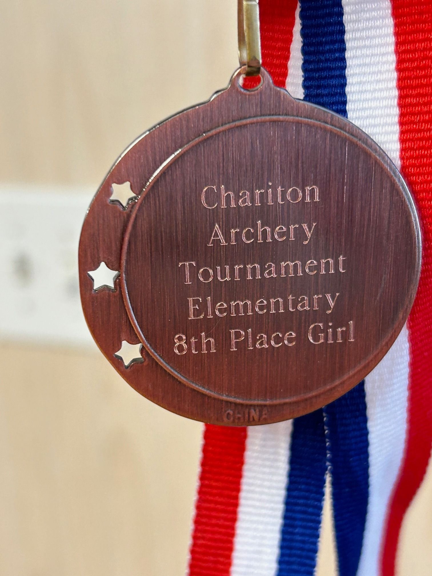 A medal that says chariton archery tournament elementary 8th place girl
