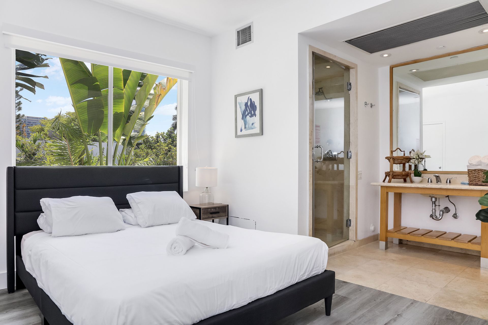Bedroom with a bed, large window with view, and an adjacent bathroom with a vanity.